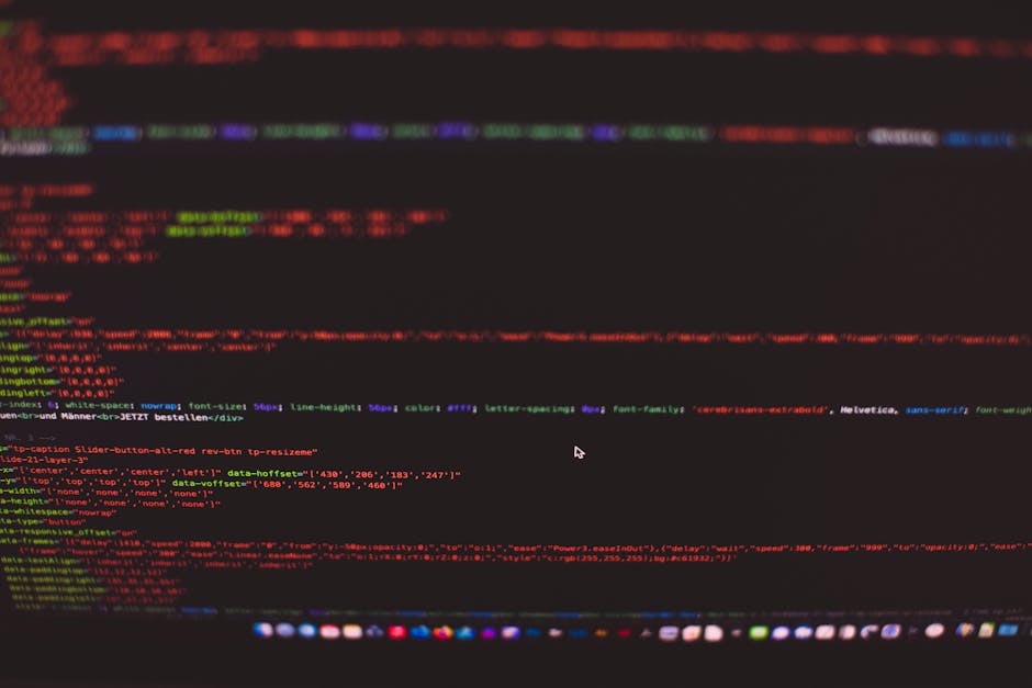A close-up view of a computer screen displaying a dark background with lines of colorful code in shades of red, green, blue, and purple. The code is slightly blurred, indicating a focus on the digital